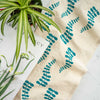 Turquoise leaf design printed on a natural cotton tea towel